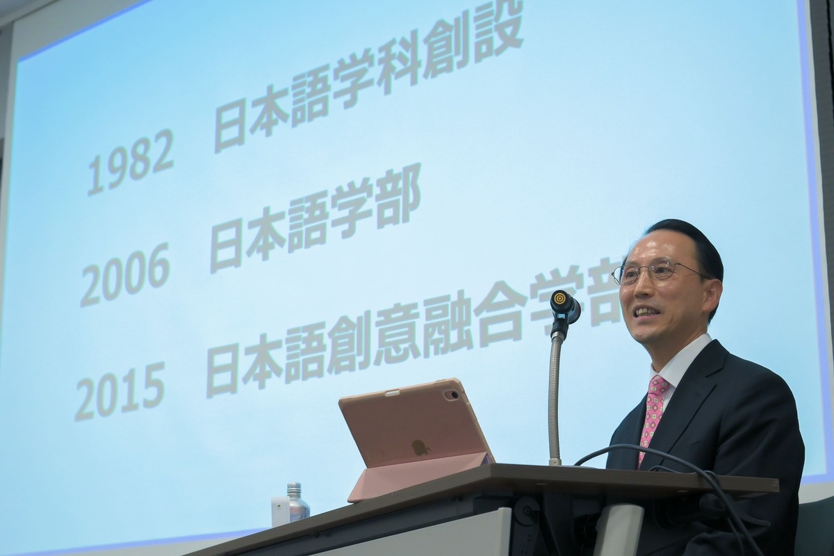 JUNG Giyoung giving a presentation in front of a slide displaying a timeline of Japanese language education