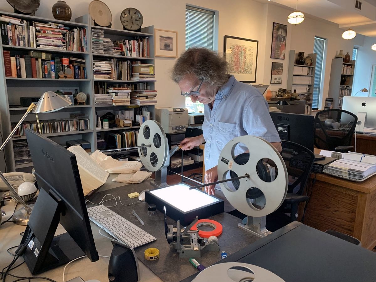 Marty Gross working at a desk handling film reels and reviewing footage in a studio-like workspace