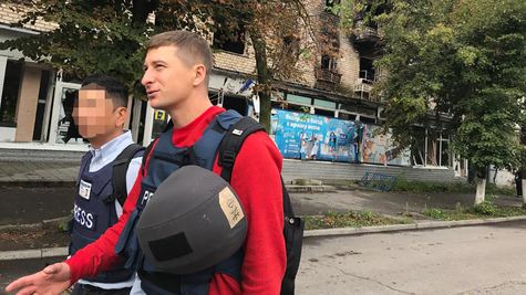 Two men walking down a street wearing bulletproof vests with the word PRESS written on them