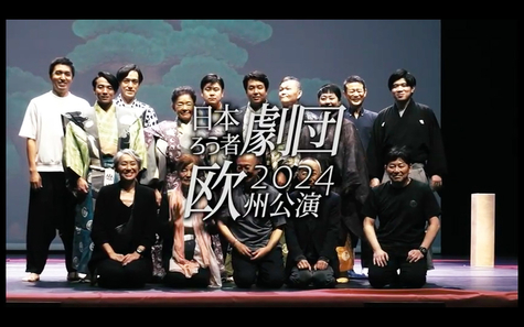 A group photo of those involved in the Paris performance, posing on stage. The image is overlaid with the Japanese text 