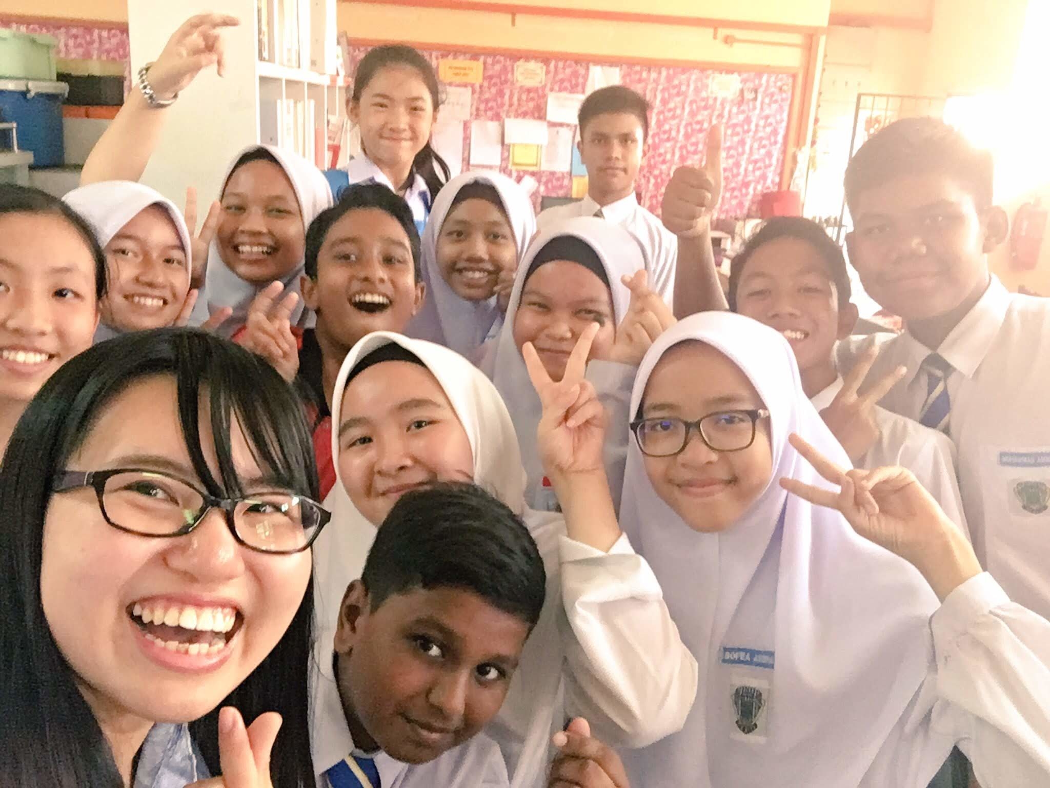 Secondary school students and their teacher in Malaysia posing for a group photo in a classroom