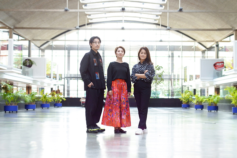広々とした屋内空間で、松田崇弥さん、小林恵さん、忍岡真理恵さんが並んで立っている写真