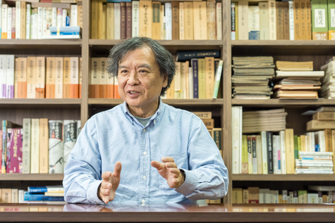 本棚の前でインタビューを受ける片渕監督 正面から